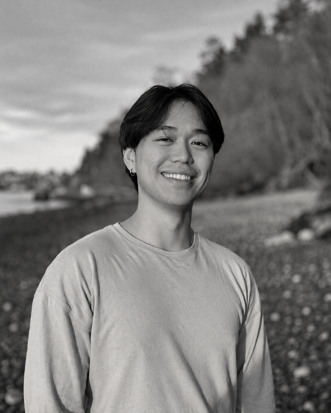 Russ Wong smiling on the beach, in black and white